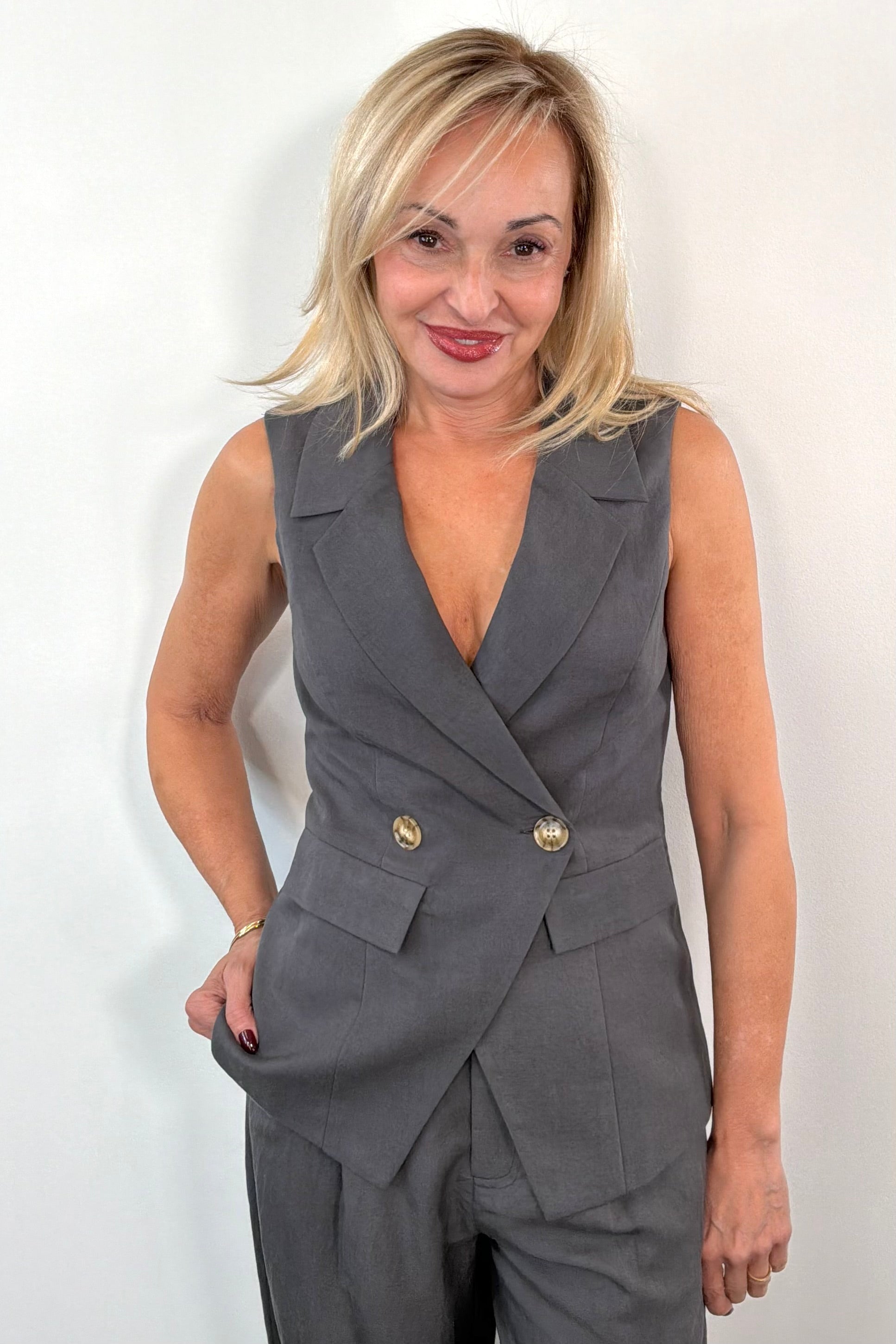 Woman wearing a grey vest with button detail