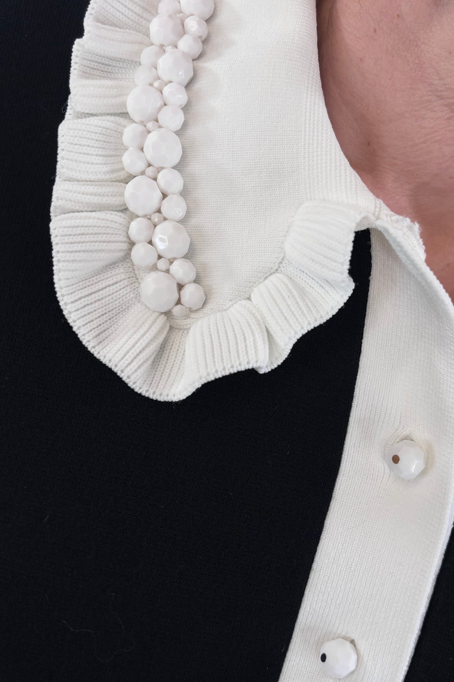 Close up of Woman wearing a black polo with white collar
