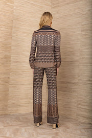 Back view of woman wearing a matching black, brown and mustard yellow patterned blouse and pants with