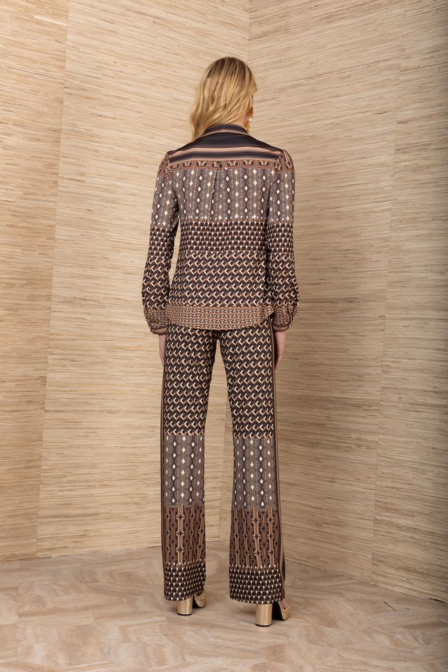 Back view of woman wearing a matching black, brown and mustard yellow patterned blouse and pants with