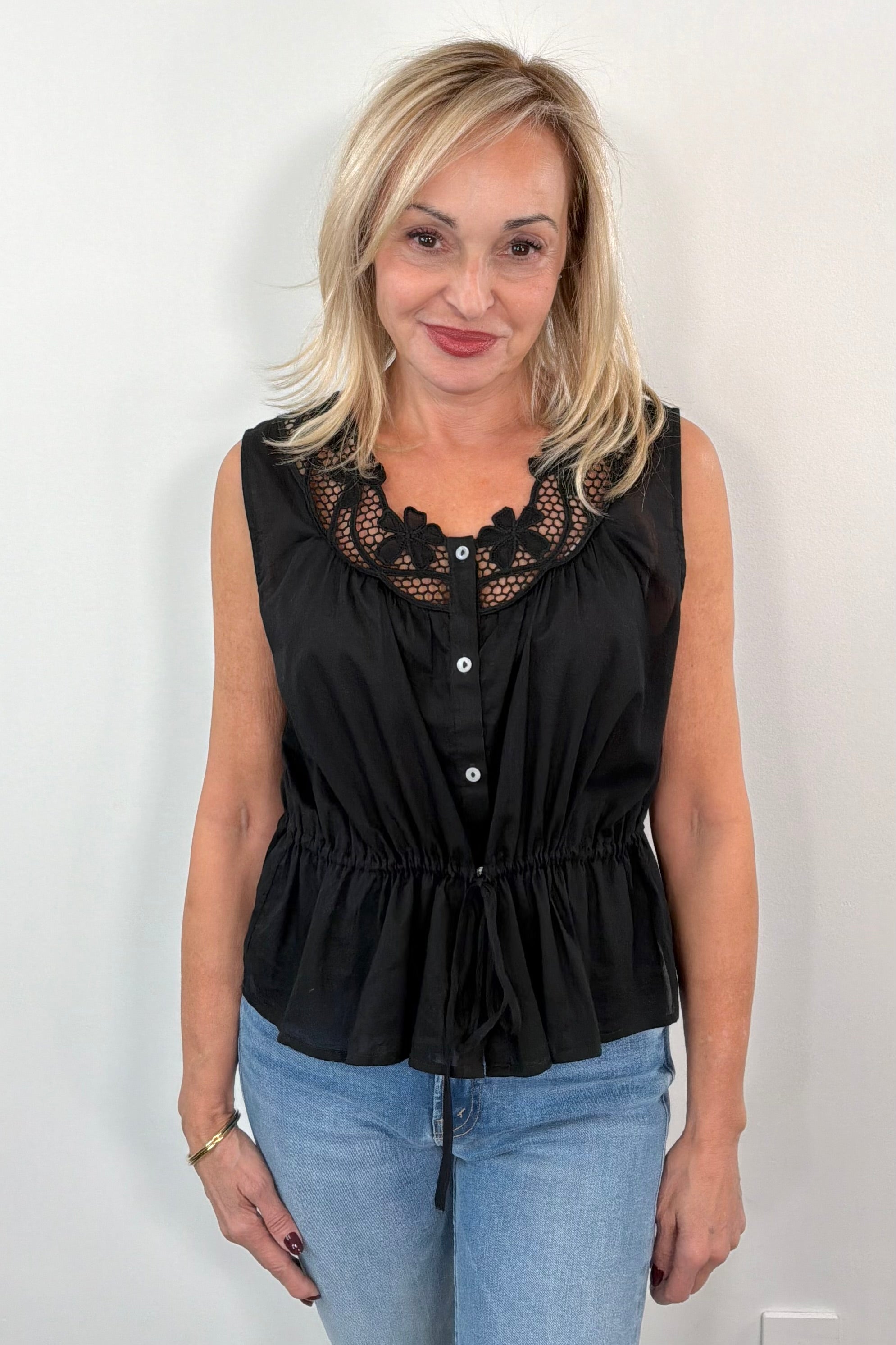 Woman wearing a sleeveless top with neckline detail in black