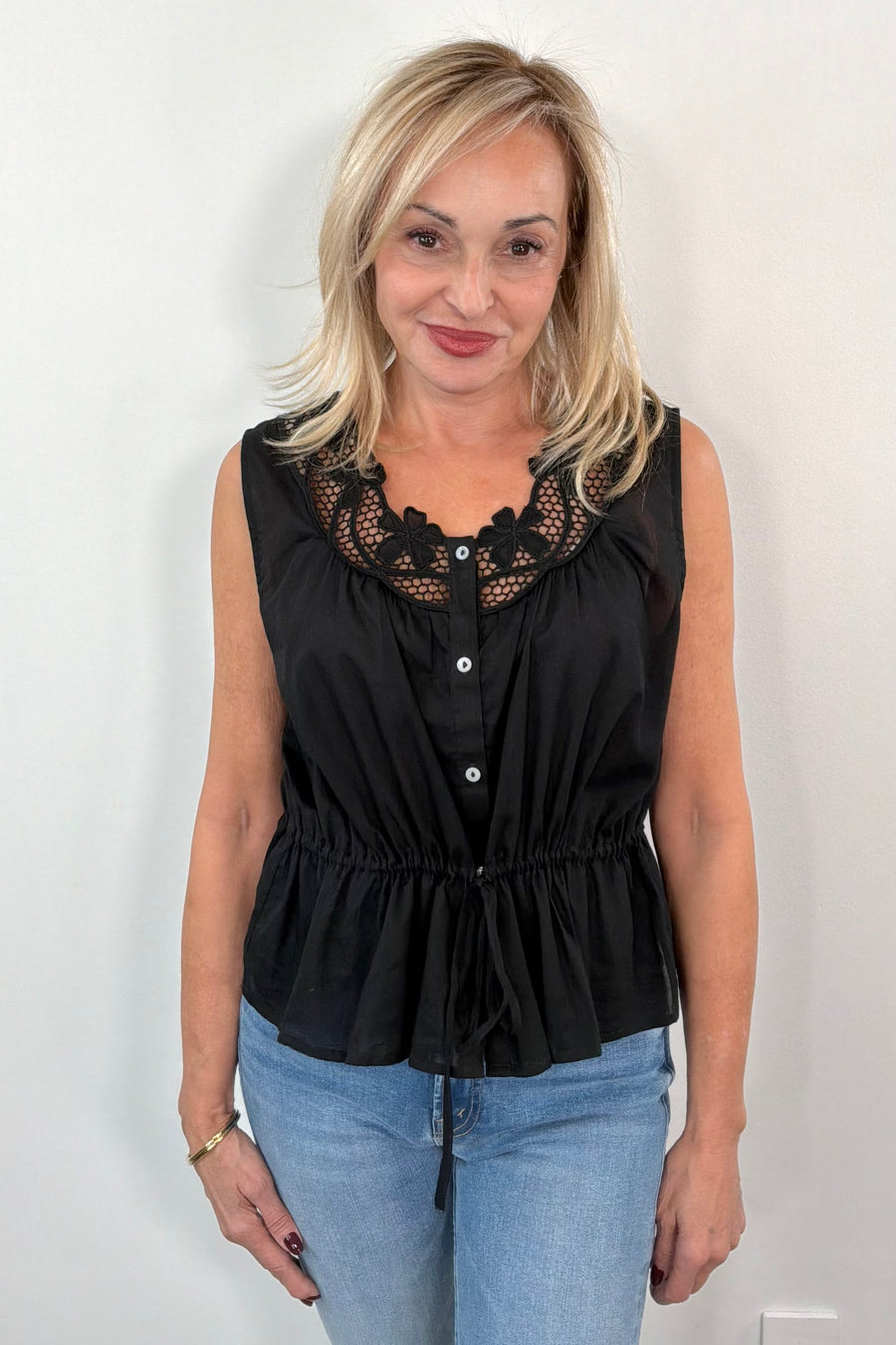 Woman wearing a sleeveless top with neckline detail in black