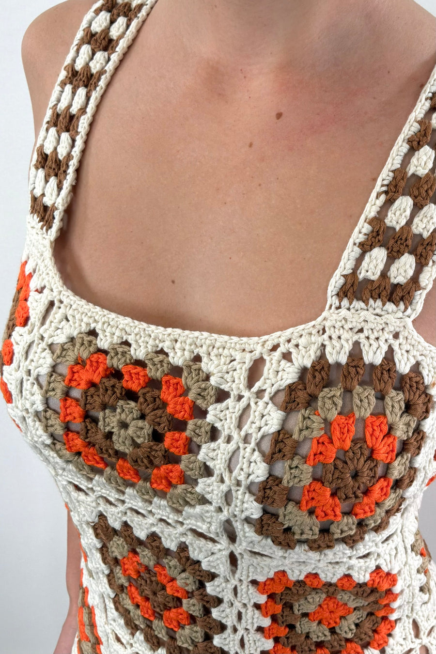 Close-up of an orange, white and beige patterned crochet short dress 
