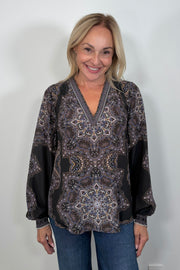 Front view of woman wearing a cuffed blouson sleeved patterned black blouse