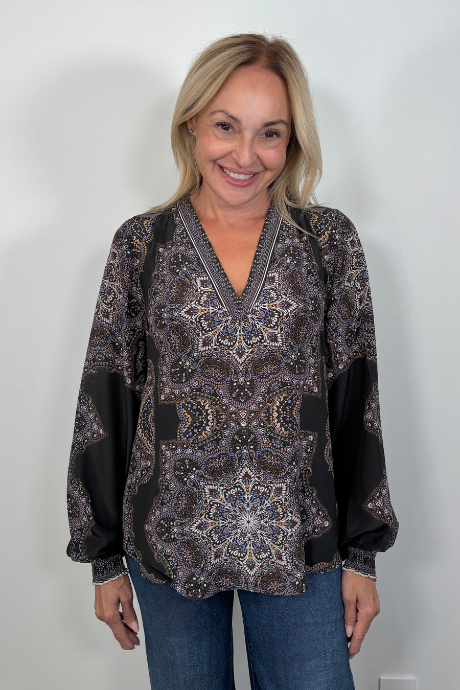 Front view of woman wearing a cuffed blouson sleeved patterned black blouse