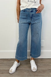 Woman wearing a light blue cropped flare denim with pockets on the front of the leg