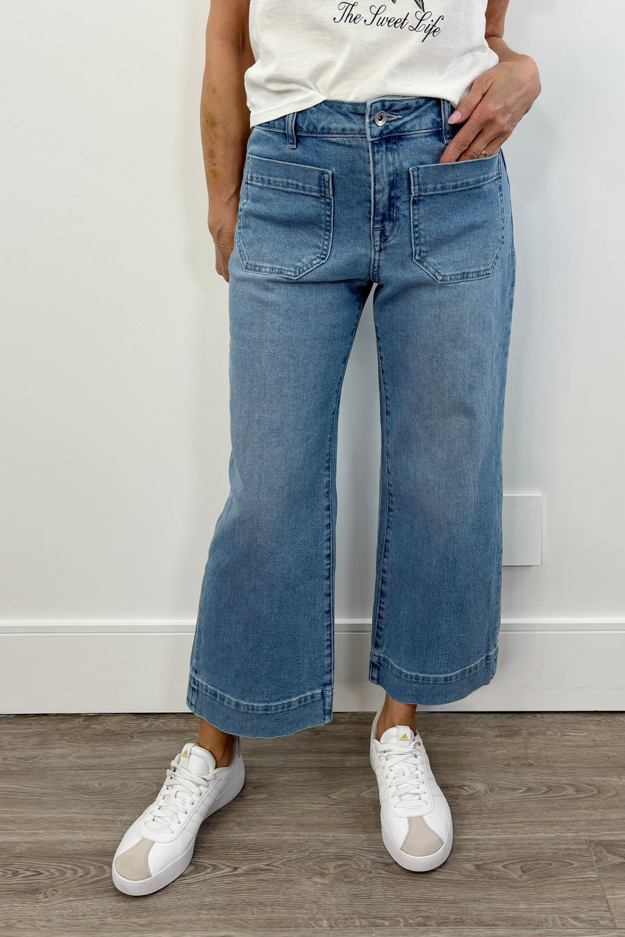 Woman wearing a light blue cropped flare denim with pockets on the front of the leg