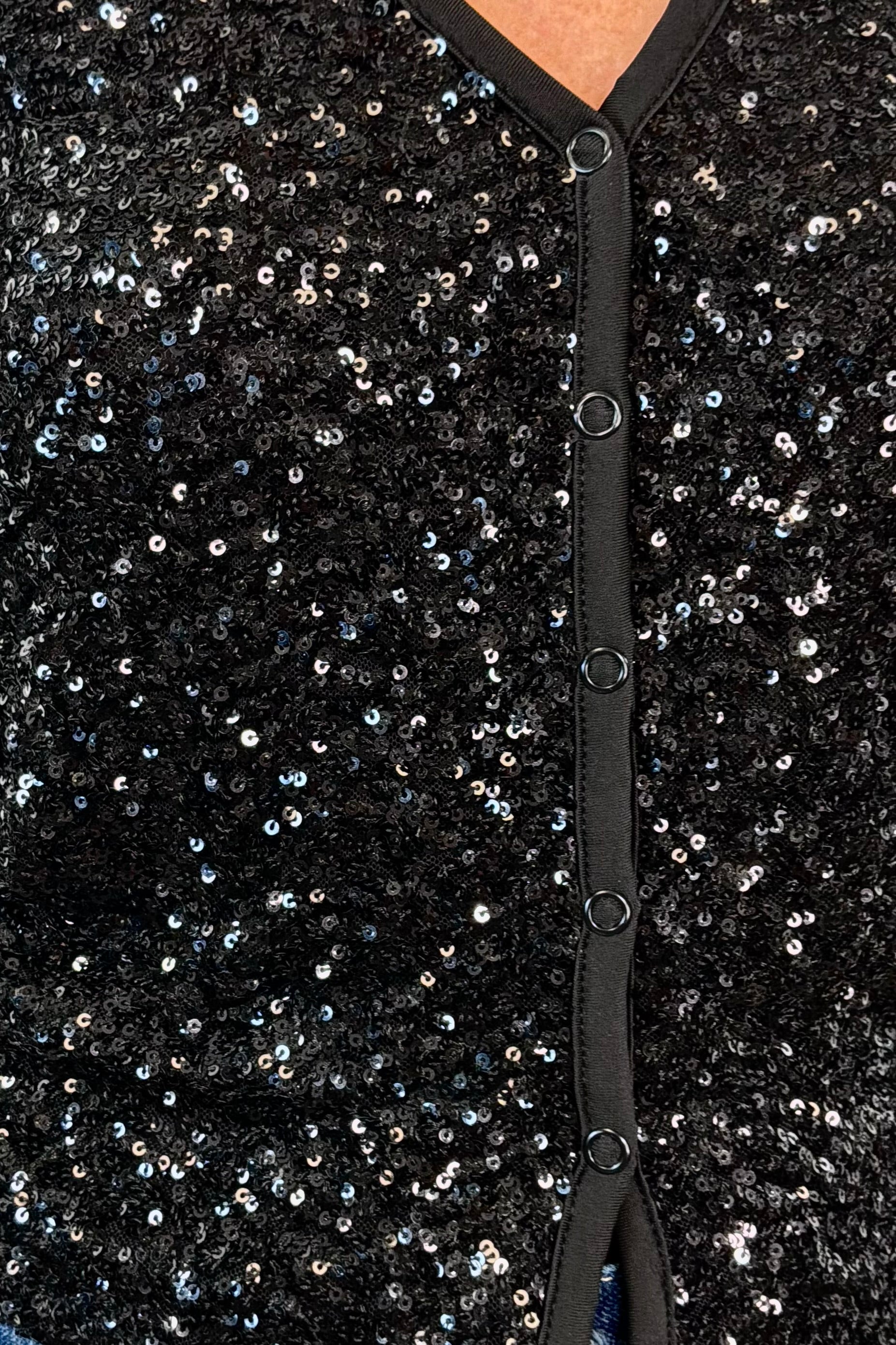 close-up of a snap on black sequin cardigan