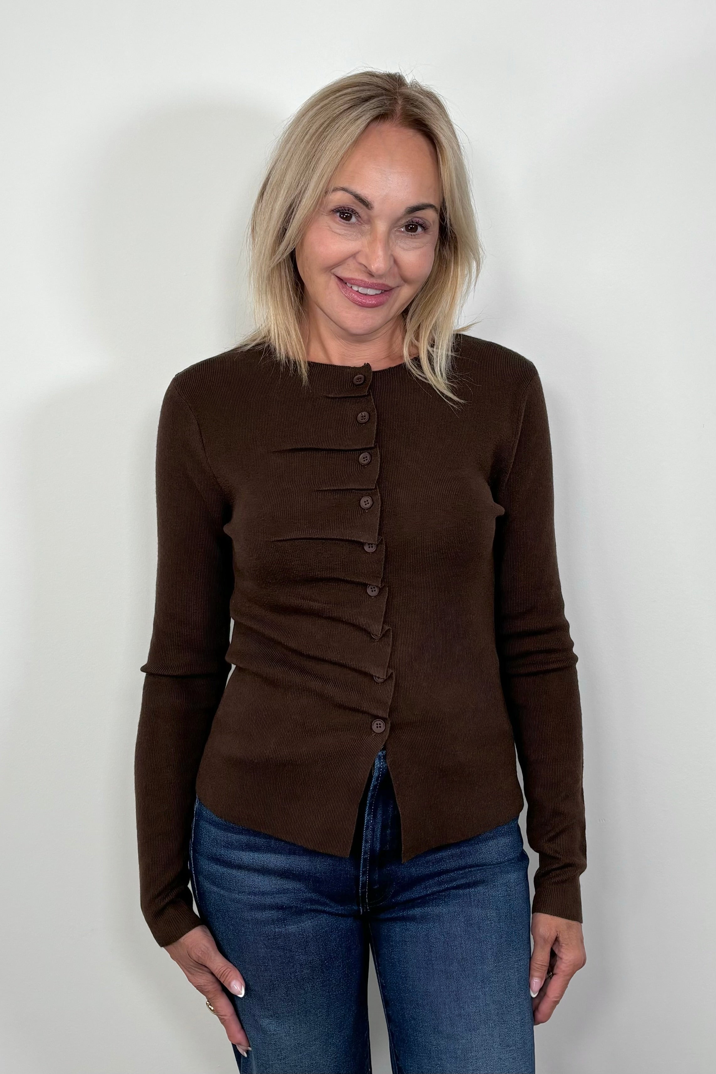 Front view of woman wearing a rouched in the buttons brown long sleeve knitted top