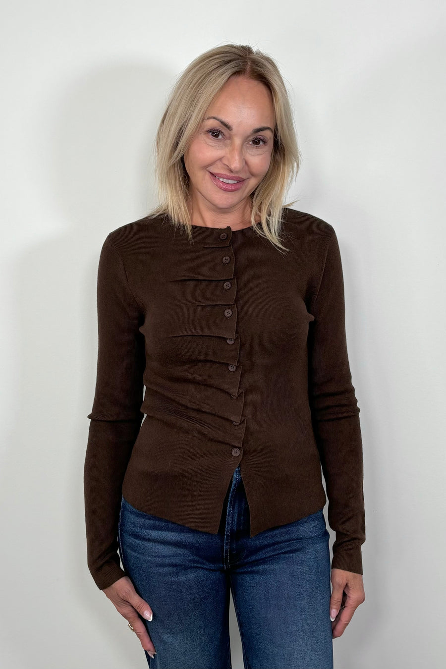 Front view of woman wearing a rouched in the buttons brown long sleeve knitted top