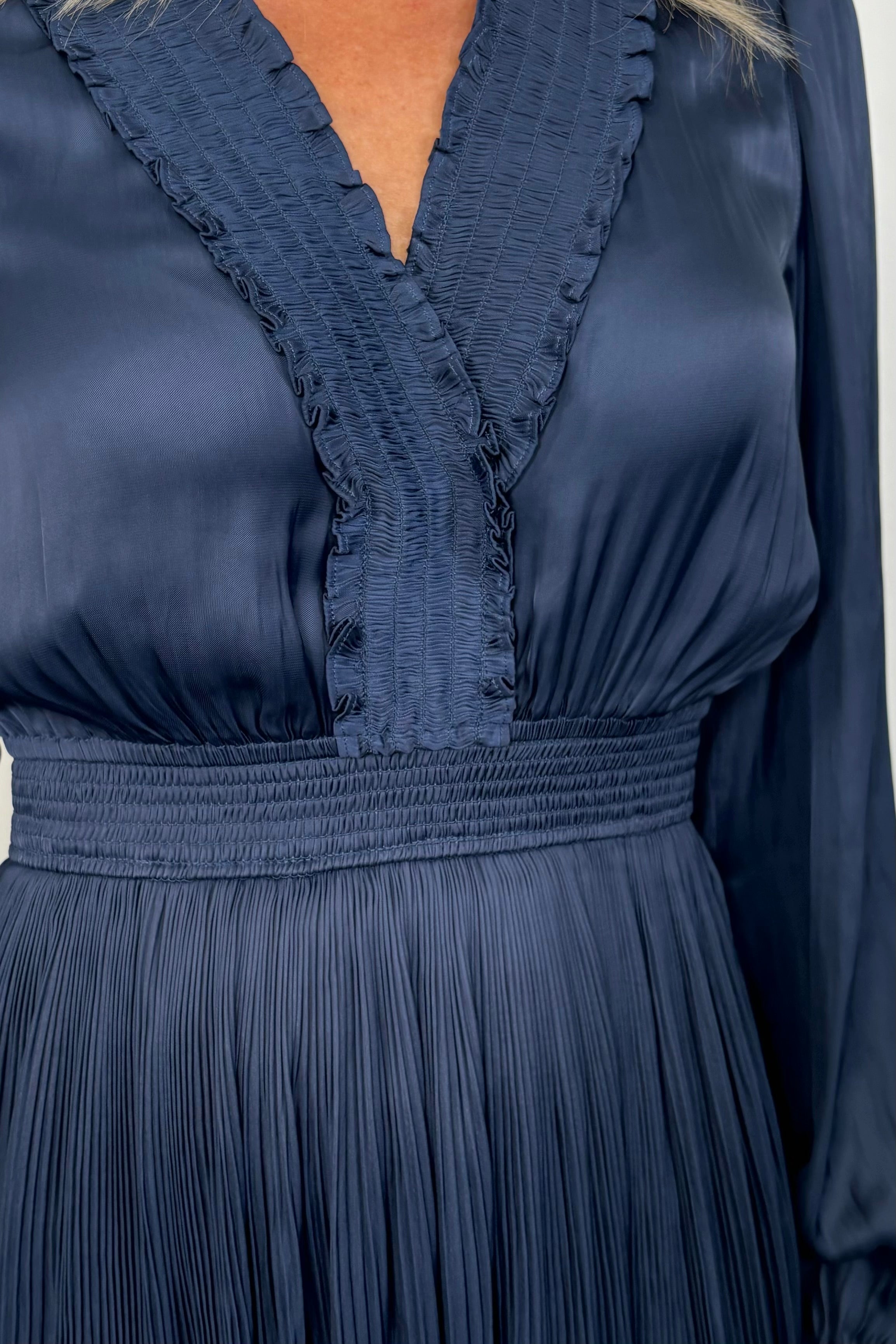 Close-up view of woman wearing a blue maxi long sleeve silk dress