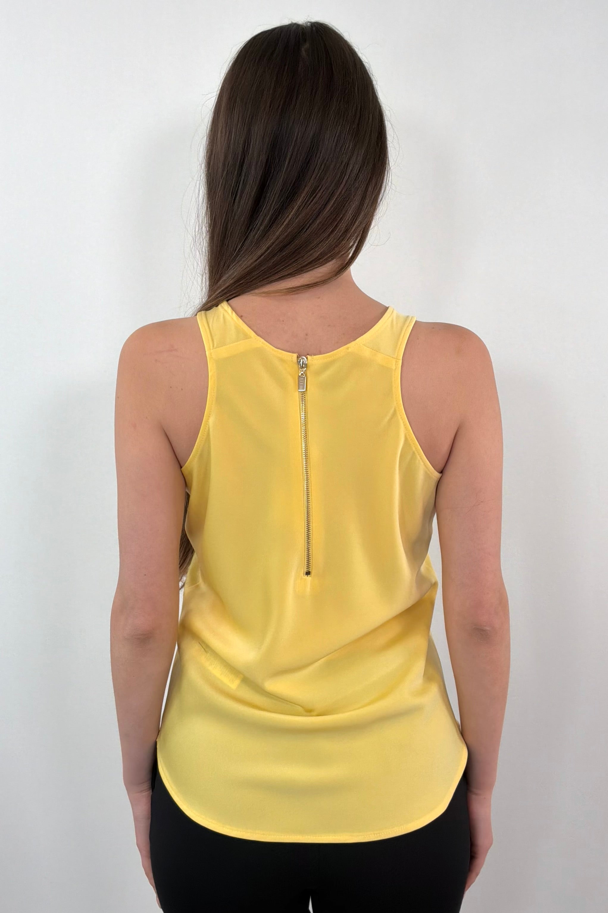 woman wearing a yellow sleeveless satin zip-up top 