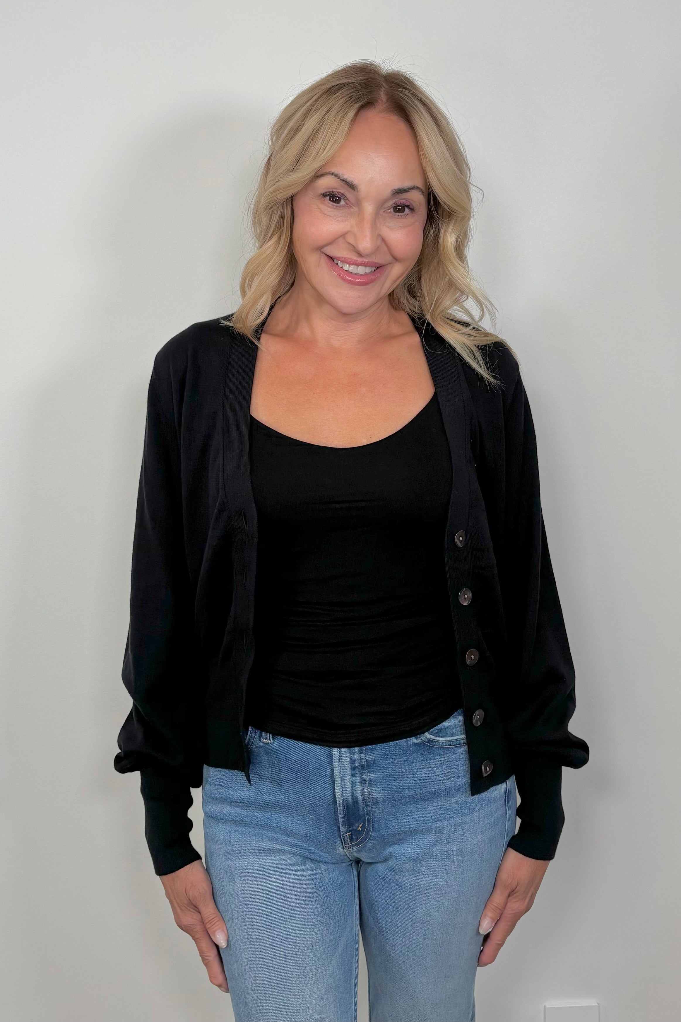 front facing woman wearing a black cotton, silk and cashmere blend cardigan with extended cuffs open.