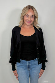 front facing woman wearing a black cotton, silk and cashmere blend cardigan with extended cuffs open.
