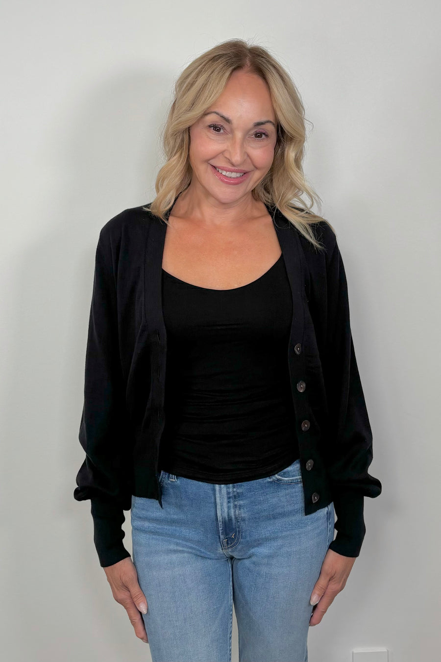 front facing woman wearing a black cotton, silk and cashmere blend cardigan with extended cuffs open.