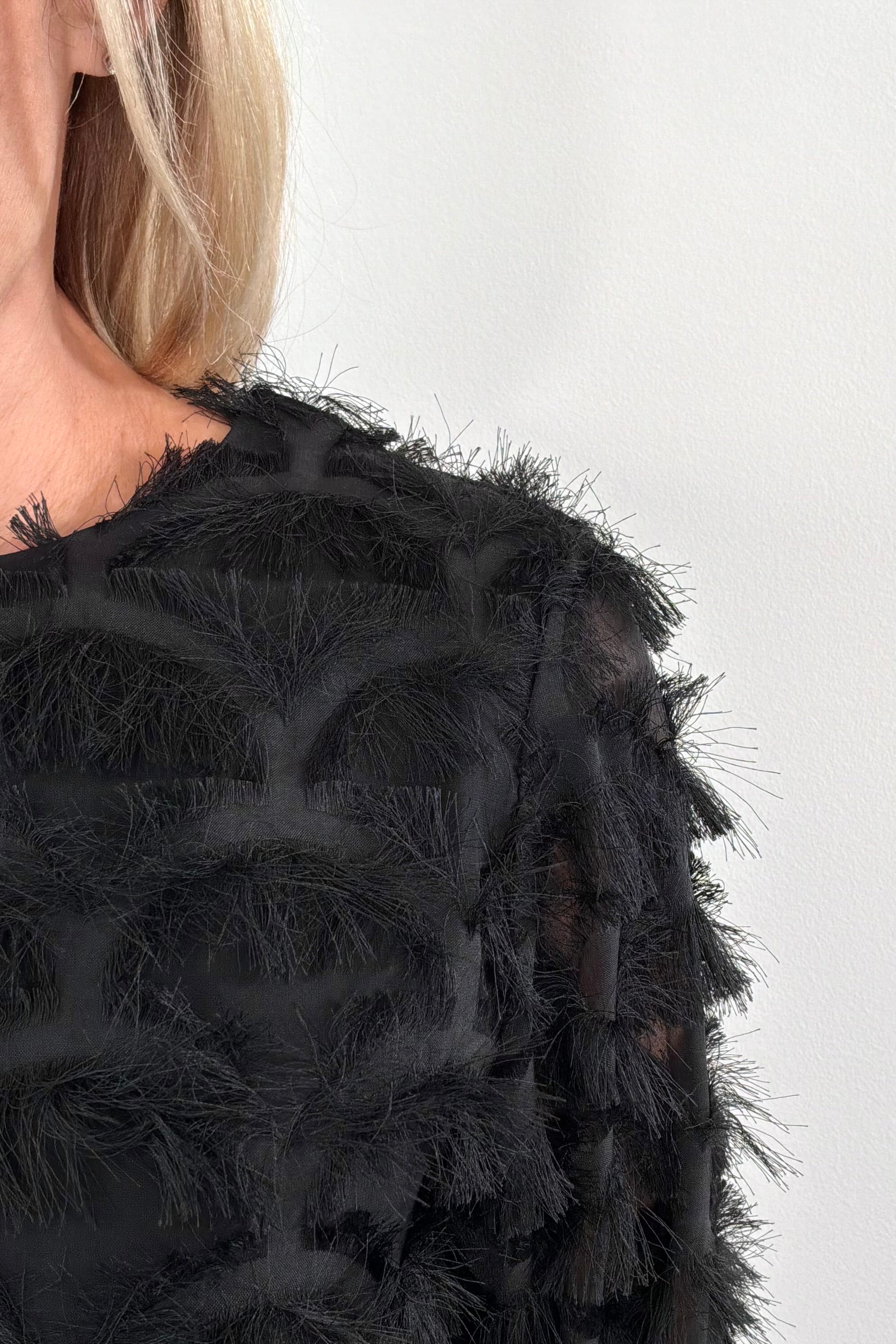 close-p of a person wearing a black top with sheer panels and frills