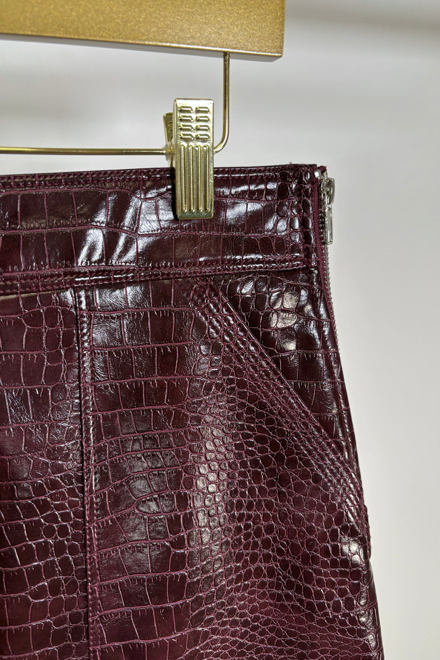 Close-up of the pocket of a short burgundy button front Russi leather skirt