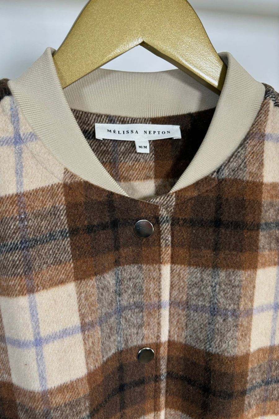Close-up of the collar of a beige/brown plaid bomber jacket