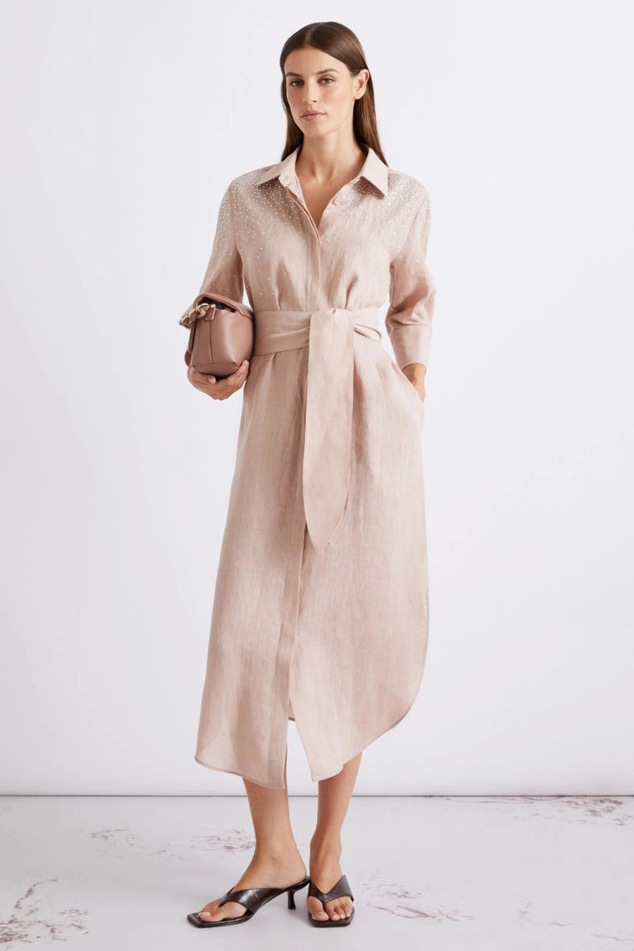 Woman wearing a blush pink collared midi dress with three-quarter sleeves, subtle embellishment, and a tie waist, front