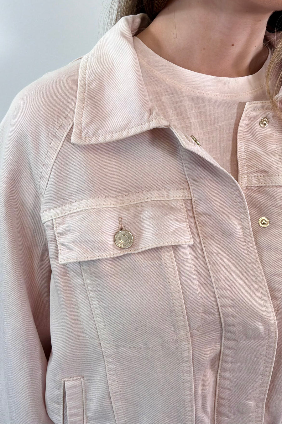 Close-up of a light pink jacket with a collar and button details