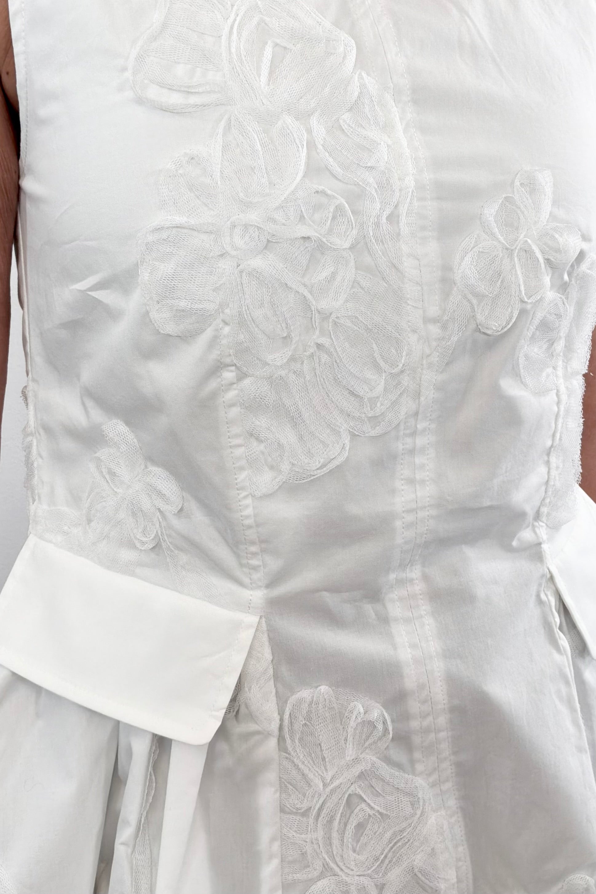 Woman wearing a white sleeveless round neck top with 3D mesh floral details 