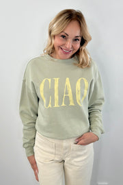 Woman wearing a matcha green pullover with " ciao " detail