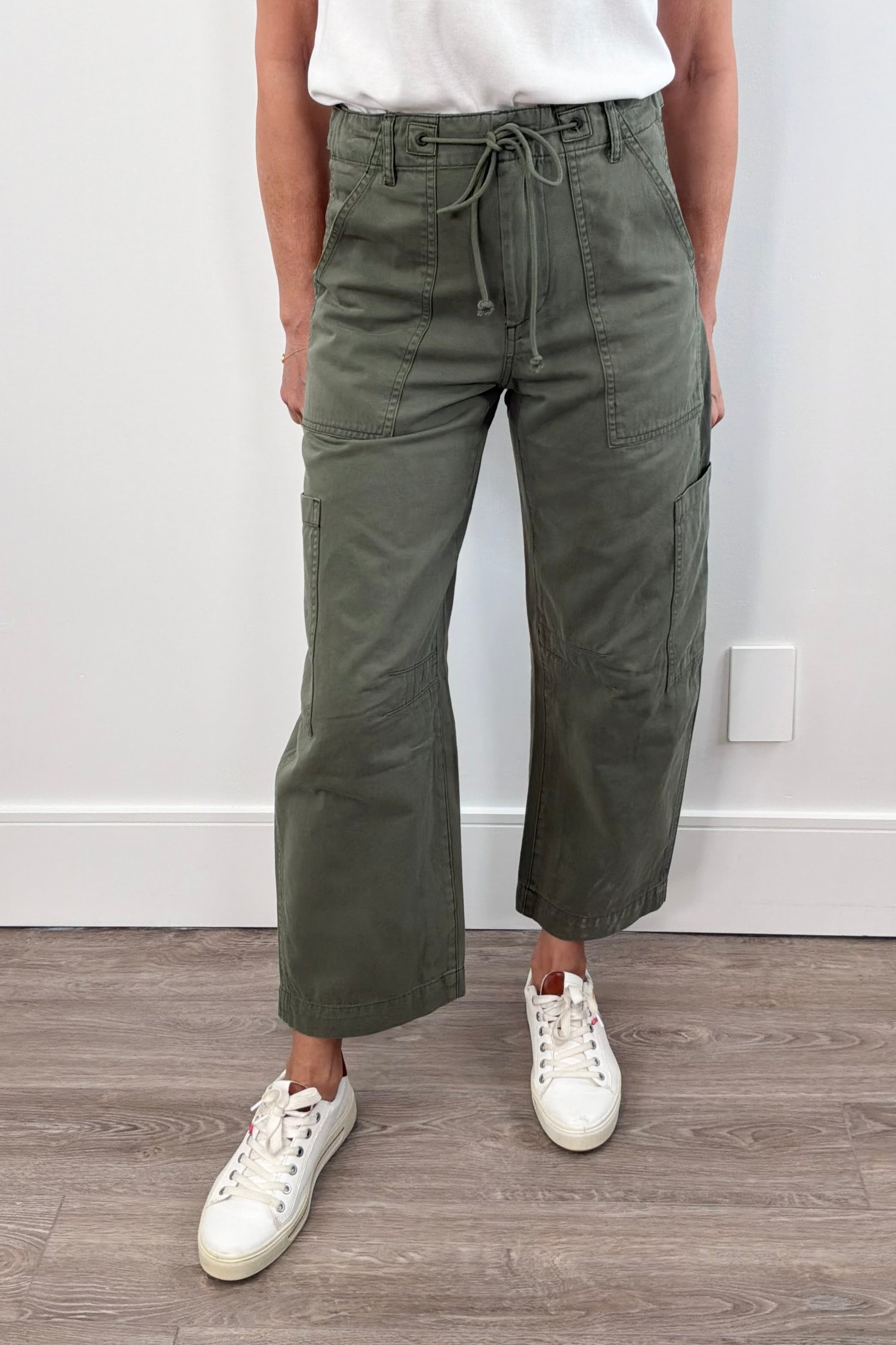 Woman wearing curved leg cargo pants with string waist in meadow green