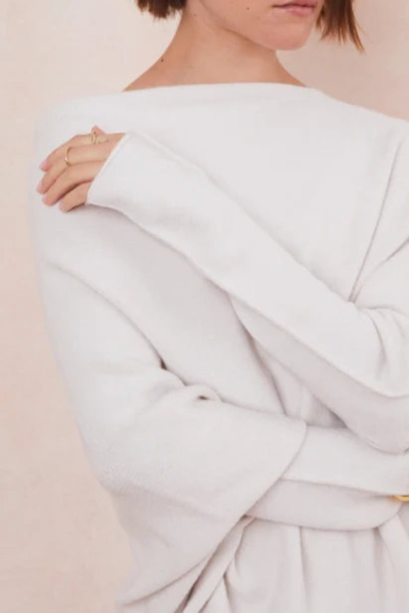 Light gray off-shoulder top worn by a person on a beige background