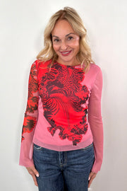 woman wearing a pink bell sleeve mesh lined top with a red orchid print