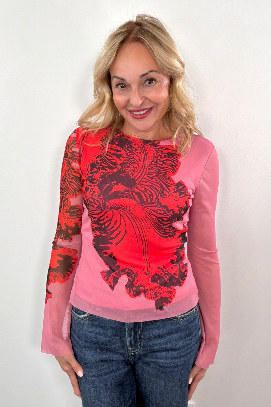 woman wearing a pink bell sleeve mesh lined top with a red orchid print