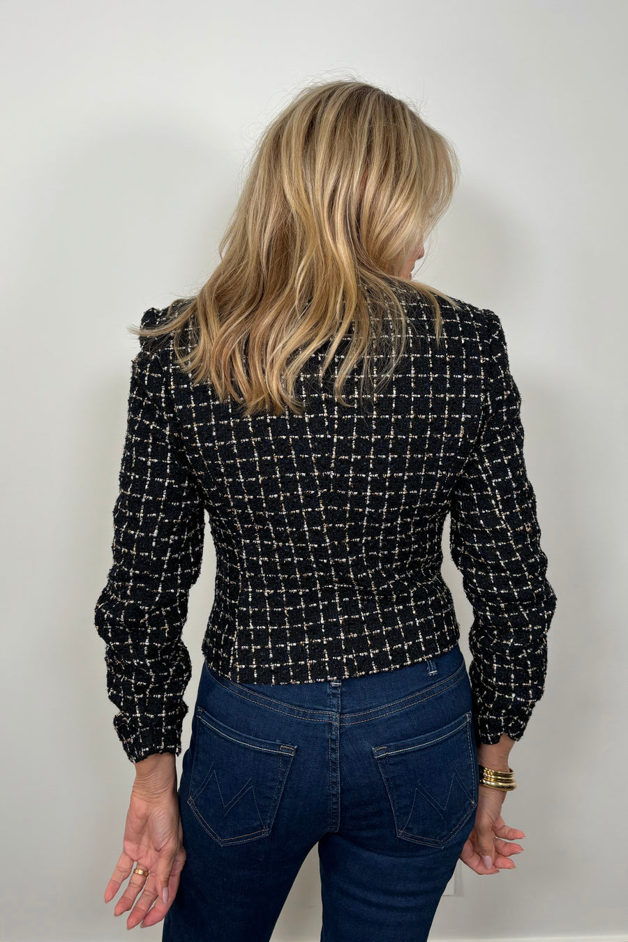 Back view of a woman wearing a navy houndstood patterned blazer with gold hardware