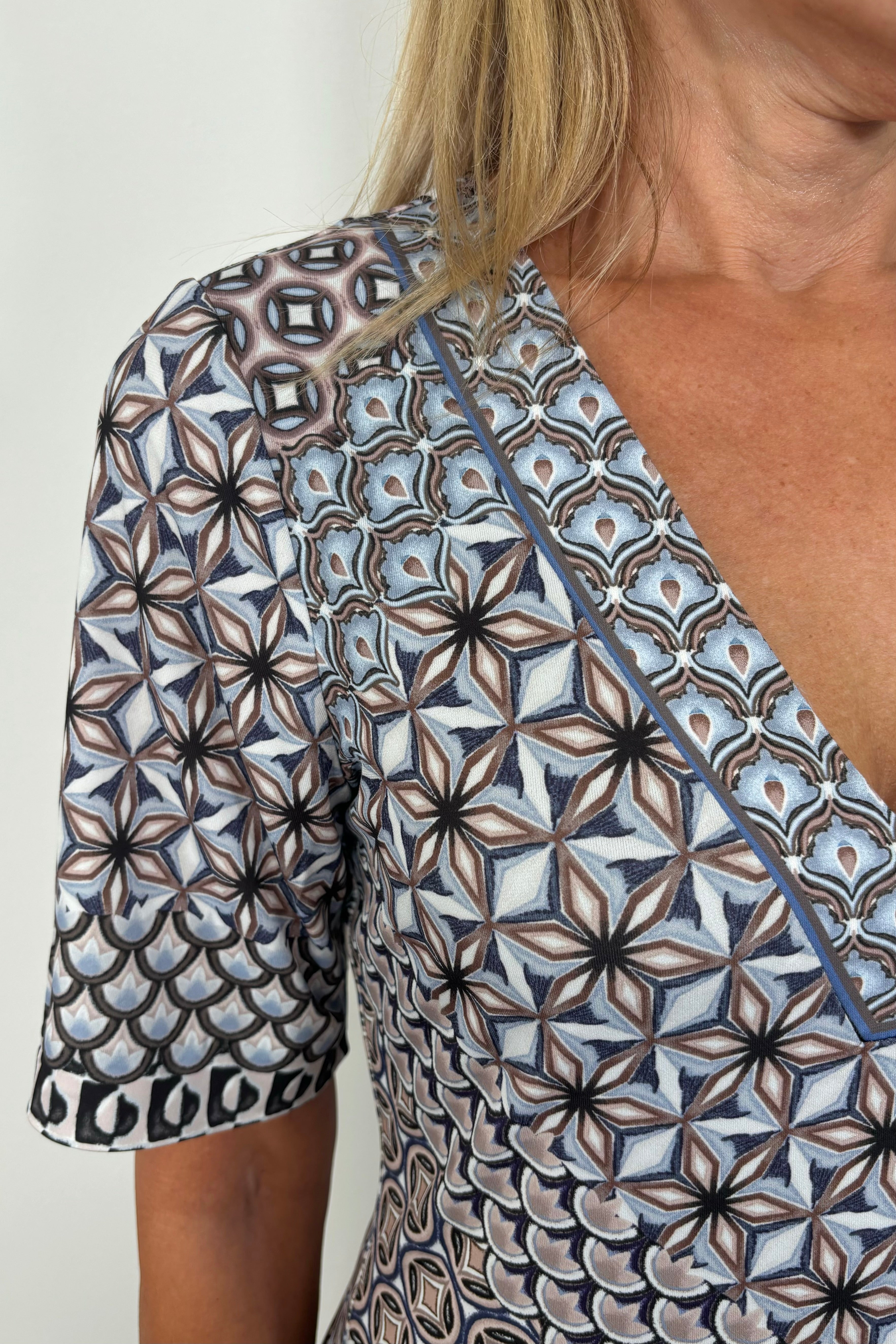 Zoom in picture of a woman’s right shoulder showing neckline detailing of a pattern in black and blue