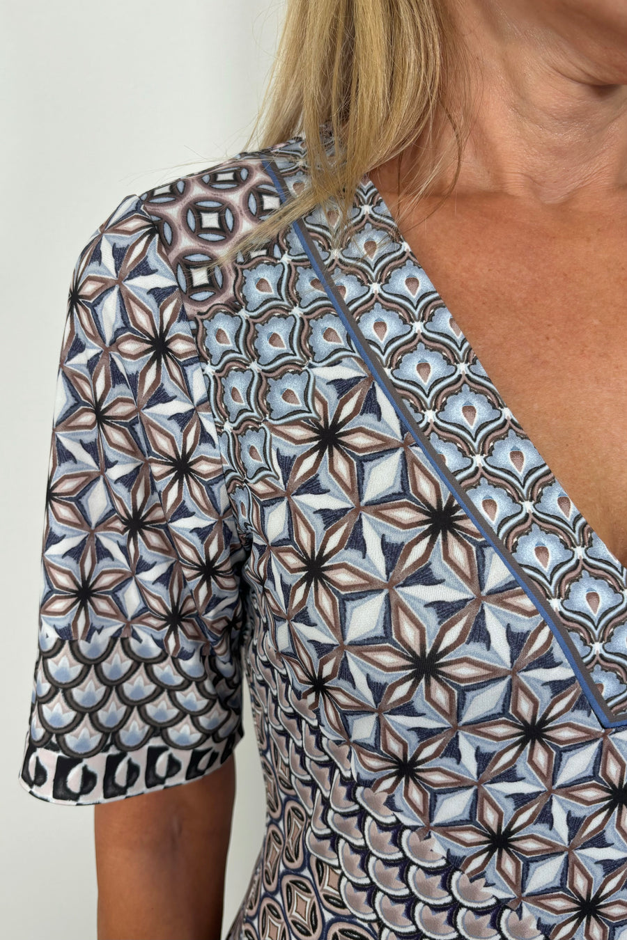 Zoom in picture of a woman’s right shoulder showing neckline detailing of a pattern in black and blue