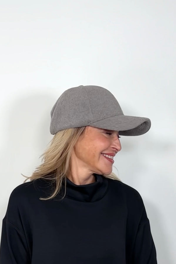 Side view of a woman wearing an light gray coloured baseball felt hat