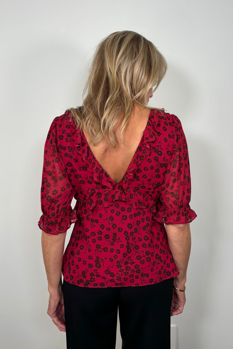Back view of woman wearing a cool red chiffon top with a daisy pattern