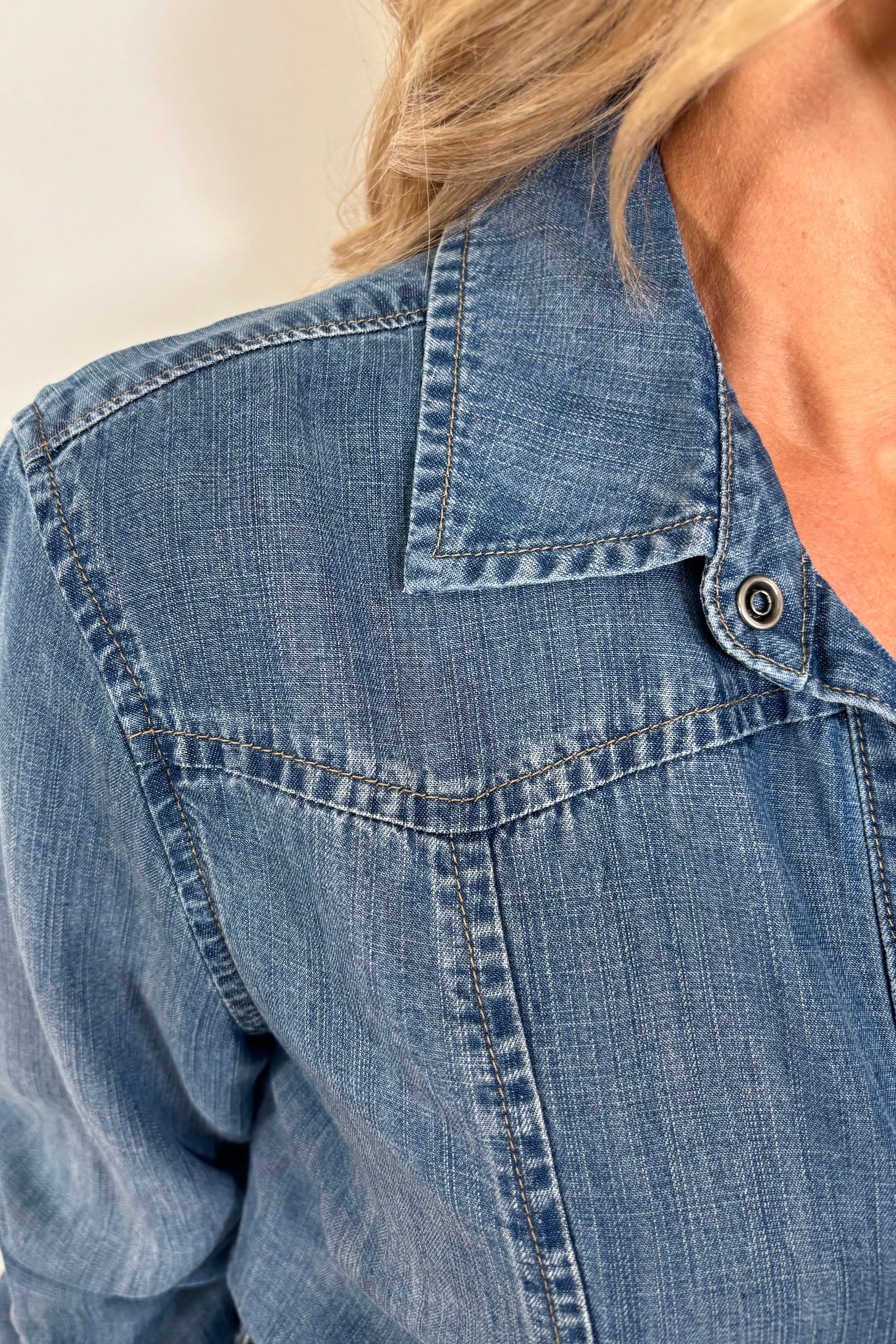 Close-up of a blue denim tencel dress with a neutral background