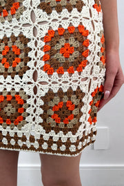 Close-up of an orange, white and beige patterned crochet short dress 