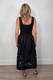 Back view of a woman wearing a black cotton dress with cut outs in the bottom