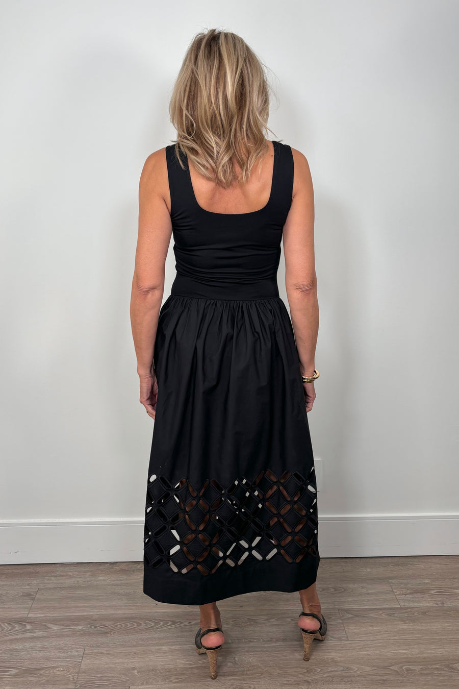 Back view of a woman wearing a black cotton dress with cut outs in the bottom