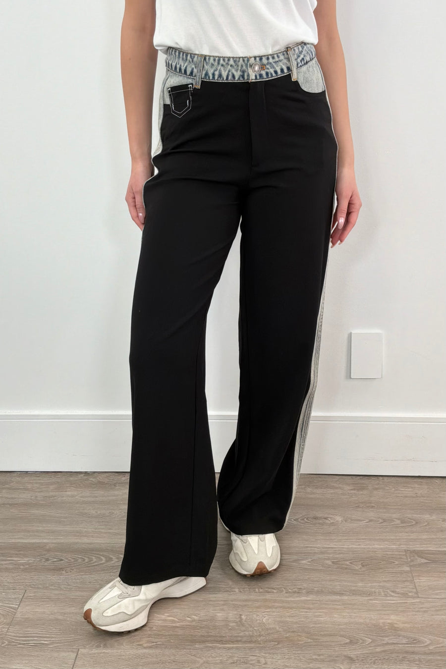 Woman wearing black dress pants with accents of light indigo denim