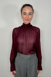 Front of woman wearing a mesh burgundy long sleeve top