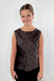 Woman wearing a brown sleeveless top with black polka dots