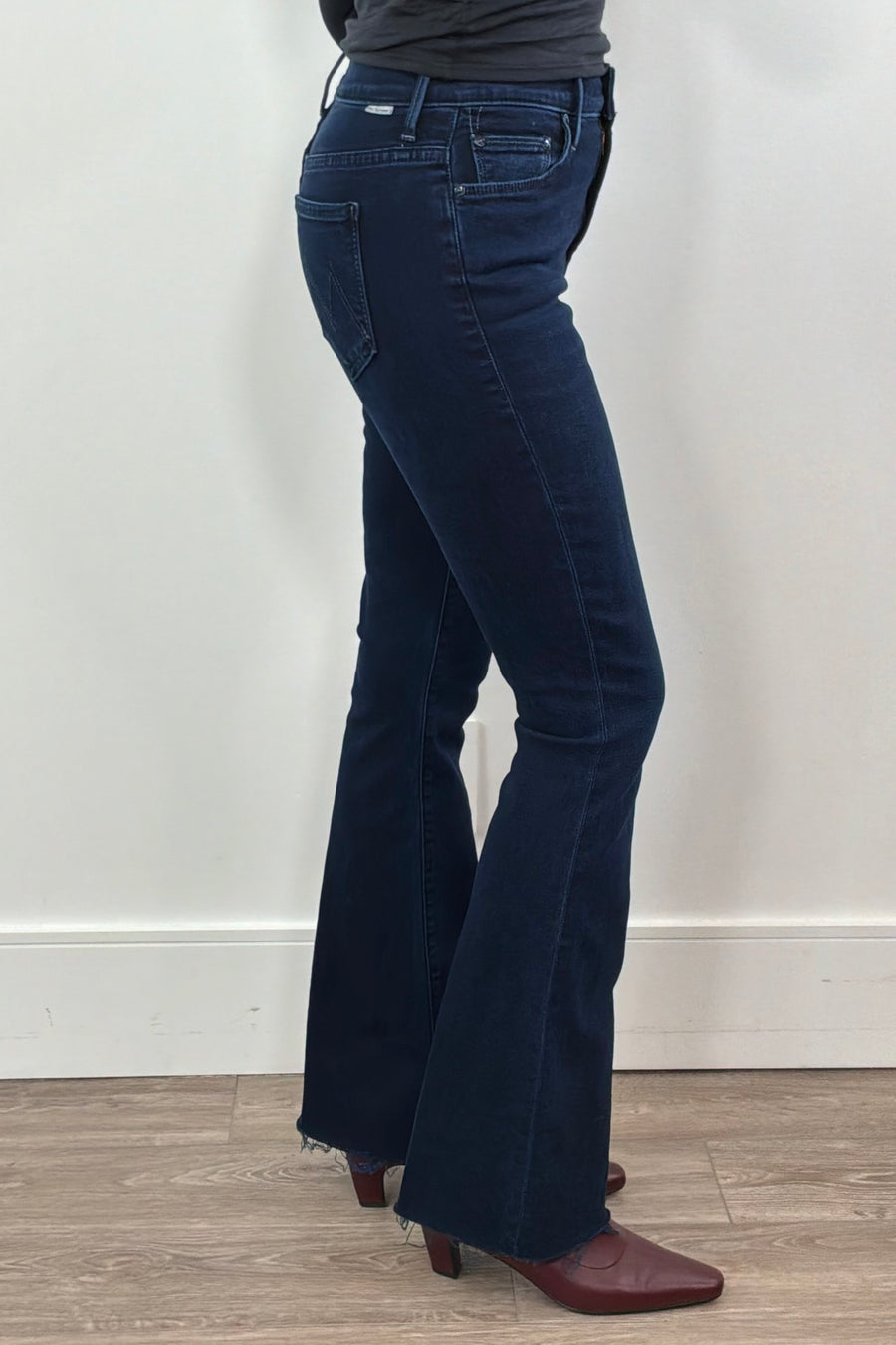 Person wearing frayed dark blue jeans 