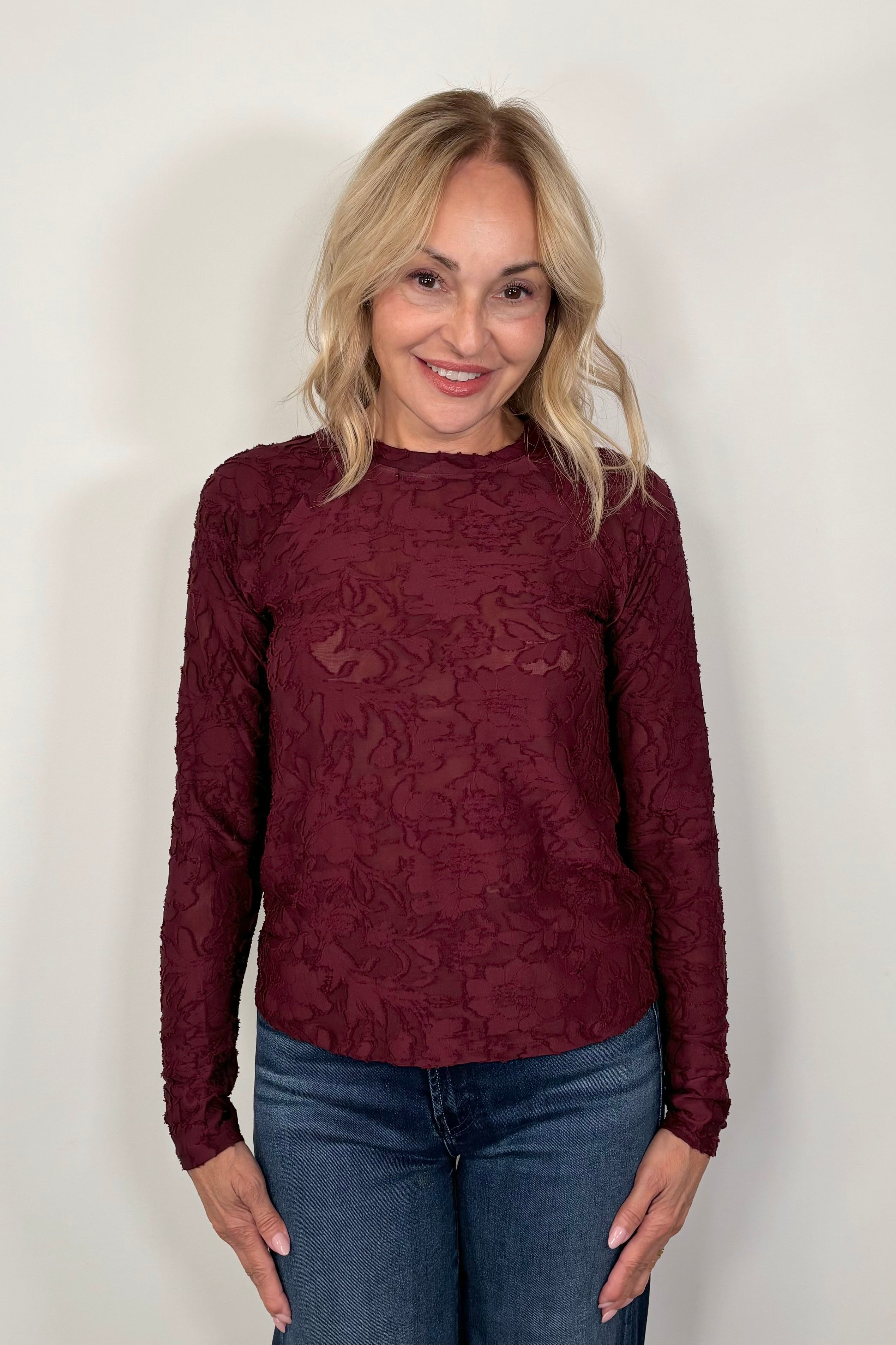 Front view of woman wearing a long sleeve burn out floral tee