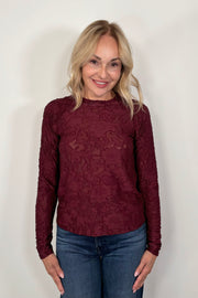 Front view of woman wearing a long sleeve burn out floral tee