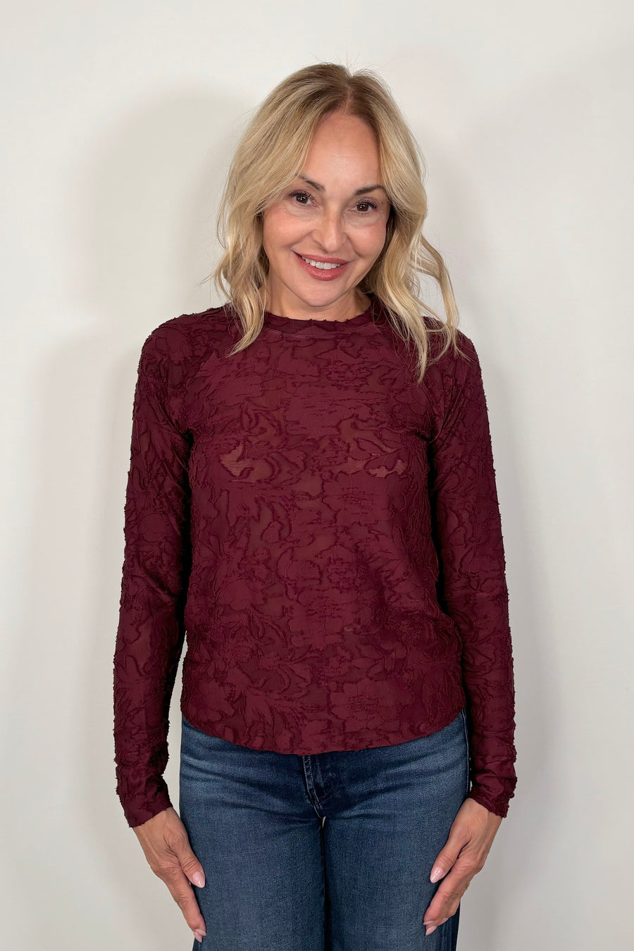 Front view of woman wearing a long sleeve burn out floral tee