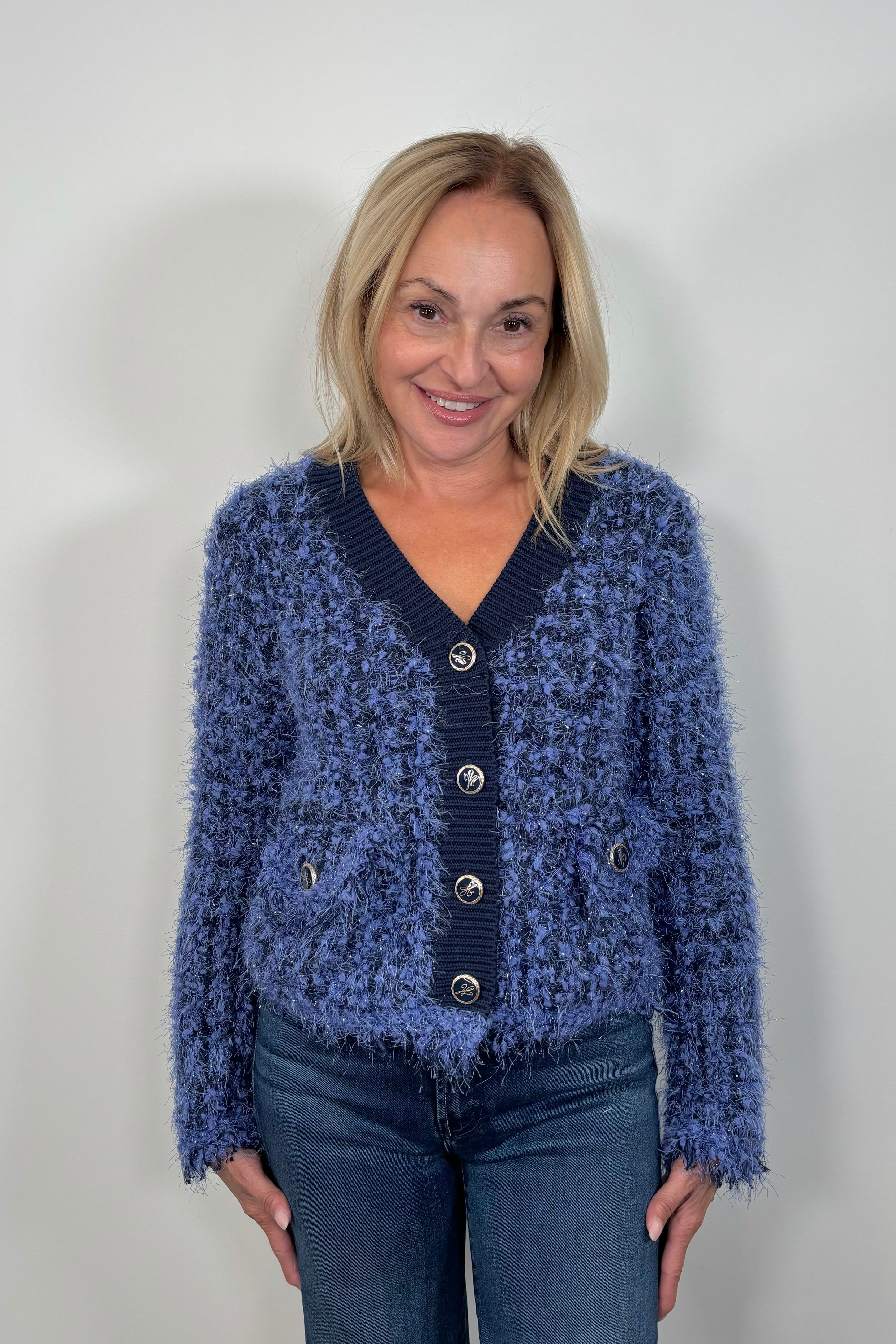 Front view of woman wearing a fluffy blue cardigan with front pockets