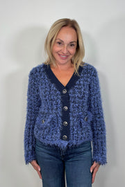 Front view of woman wearing a fluffy blue cardigan with front pockets
