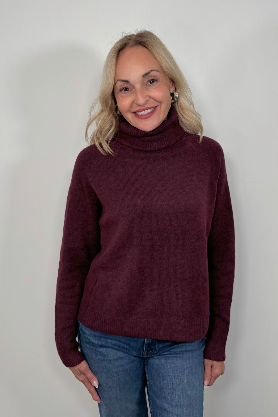 Front view of woman wearing an oversized merlot knitted turtleneck 