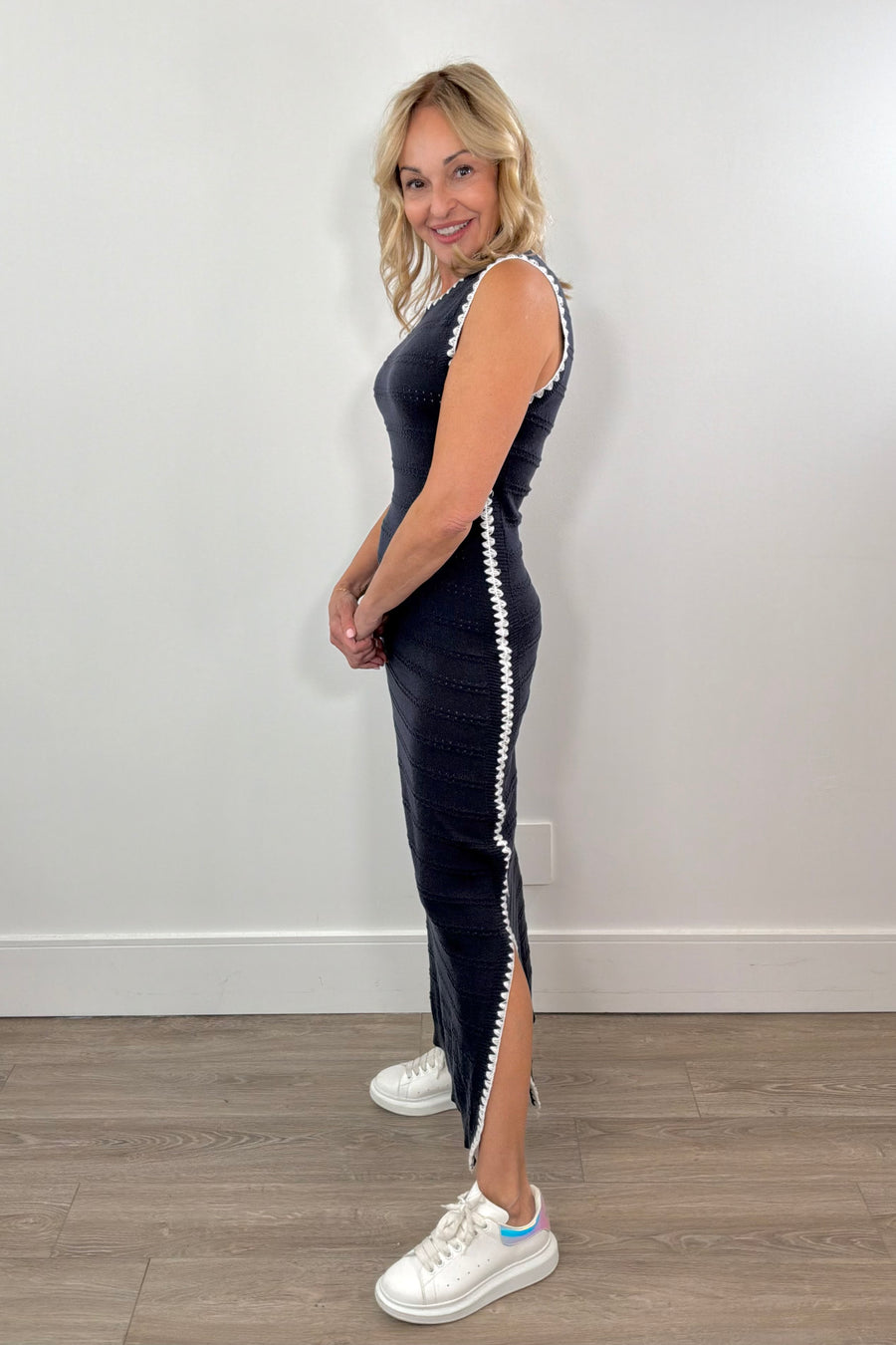 Side view of Women wearing a dark blue knit dress with white details